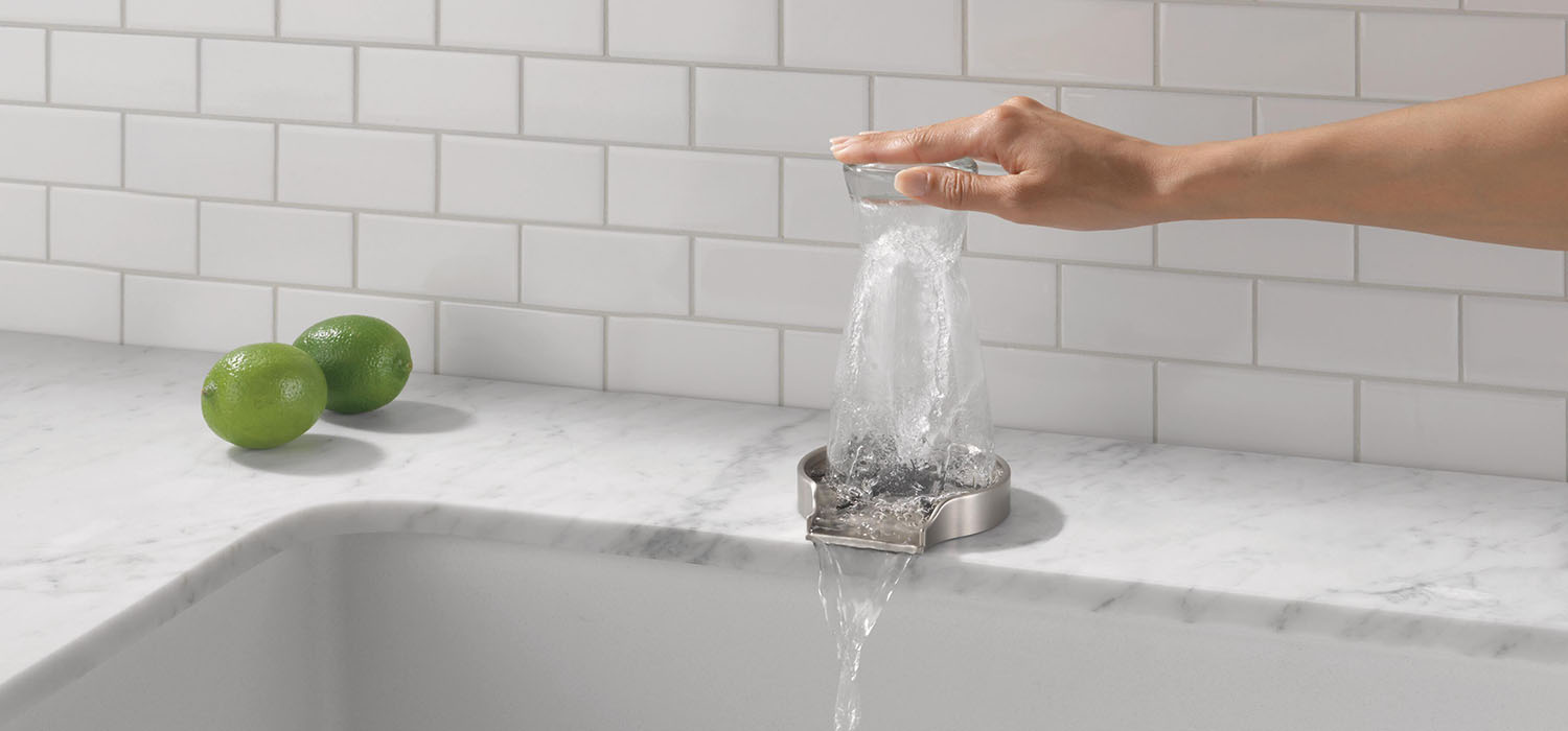 Glass Rinser being used to clean drinking glass in white kitchen