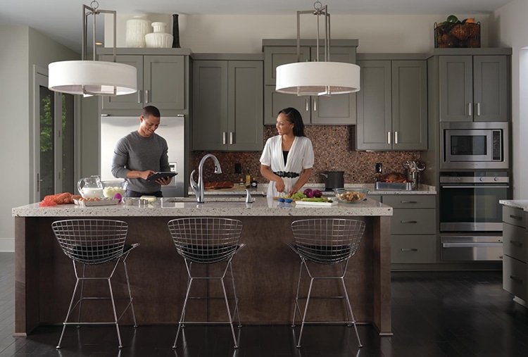 Man and woman stand in modern kitchen with grey cabinets