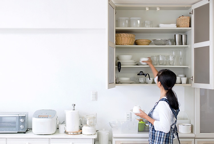 woman organizing dishes in her kitchen cabinet