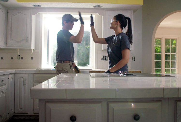Mike and Hannah give each other a high-five in a newly-remodeled kitchen
